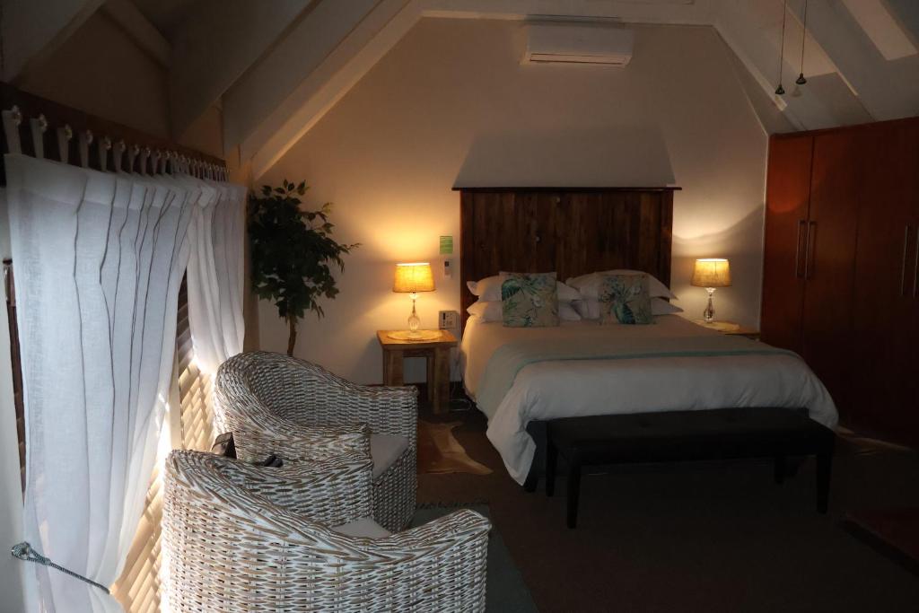 波罗瓜尼The Leopard Tree的一间卧室配有一张床和两张藤椅