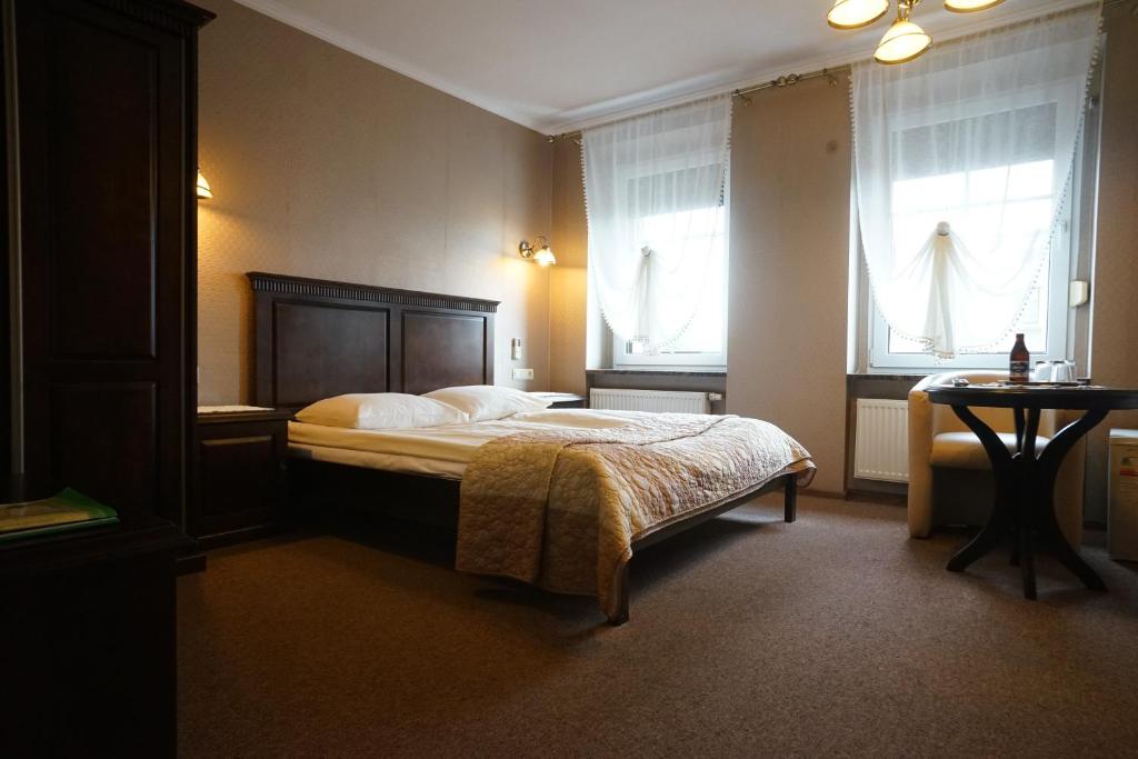 OlesnoHotel Alexandra的卧室配有床、桌子和窗户。