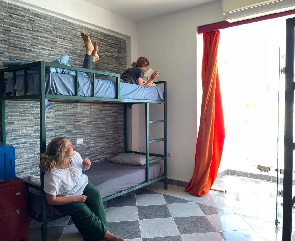 达哈布My Hostel in Dahab - Dive center的两人坐在房间双层床上