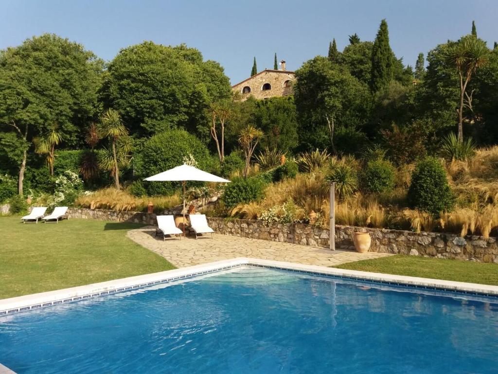 Sales del Llierca坎塞罗拉酒店的庭院内的游泳池配有椅子和遮阳伞