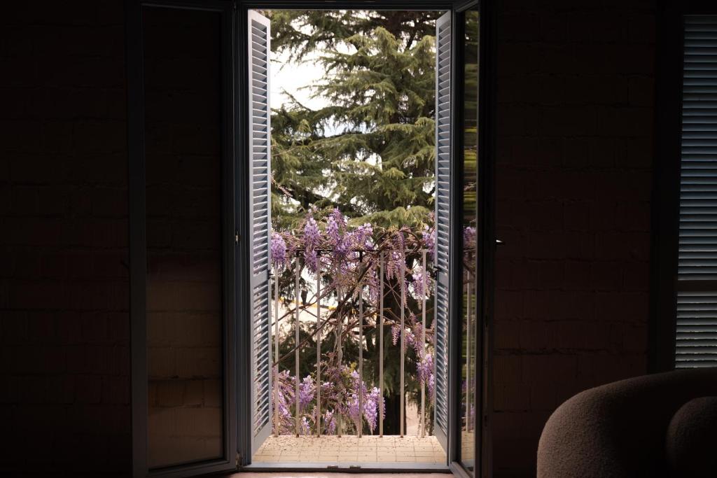 巴统Rooms Hotel Batumi的通往花园的开放式门,花园外面种有紫色花卉