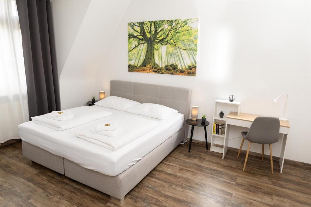 威斯巴登BeMyGuest - 3 Zimmer Maisonette - Zentral - Klimaanlage - Aufzug的一间卧室配有一张床、一张书桌和一幅画