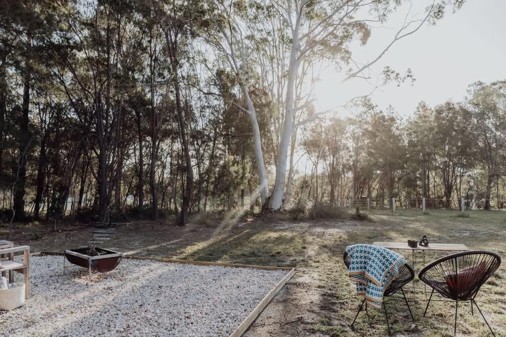 Ringtail CreekNoosa Tiny Home的公园里设有两把椅子和桌子,树木繁茂
