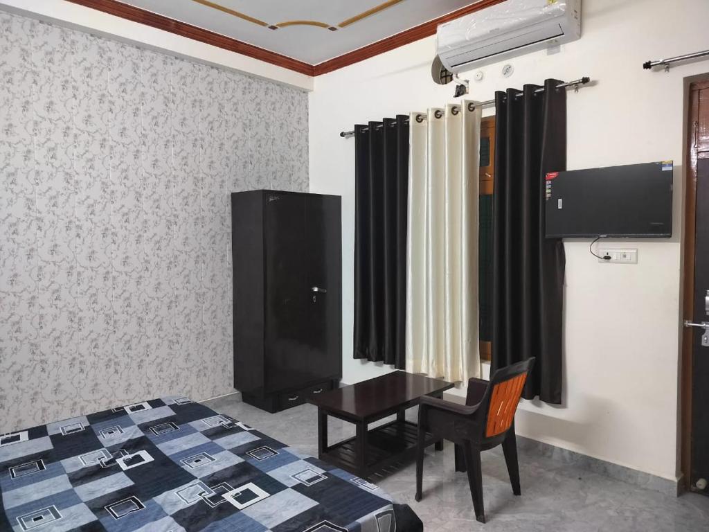 FaizābādHari Om Homestay的一间卧室配有一张床、一张书桌和一台电视。