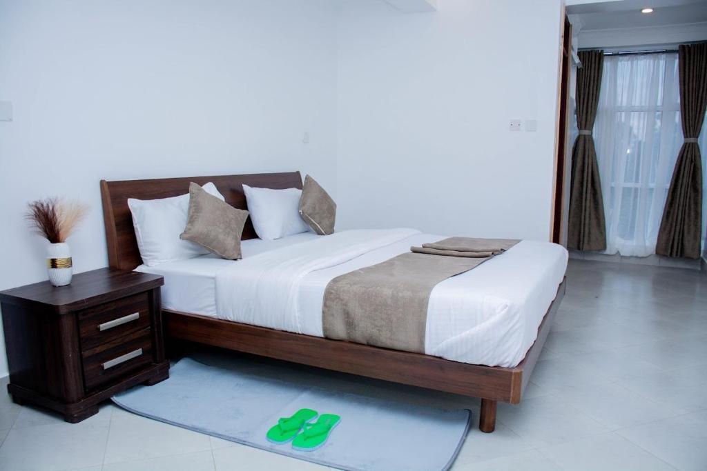 埃尔多雷特The Grand Rocks Hotel Limited的一间卧室配有一张床和一张带绿色拖鞋的桌子