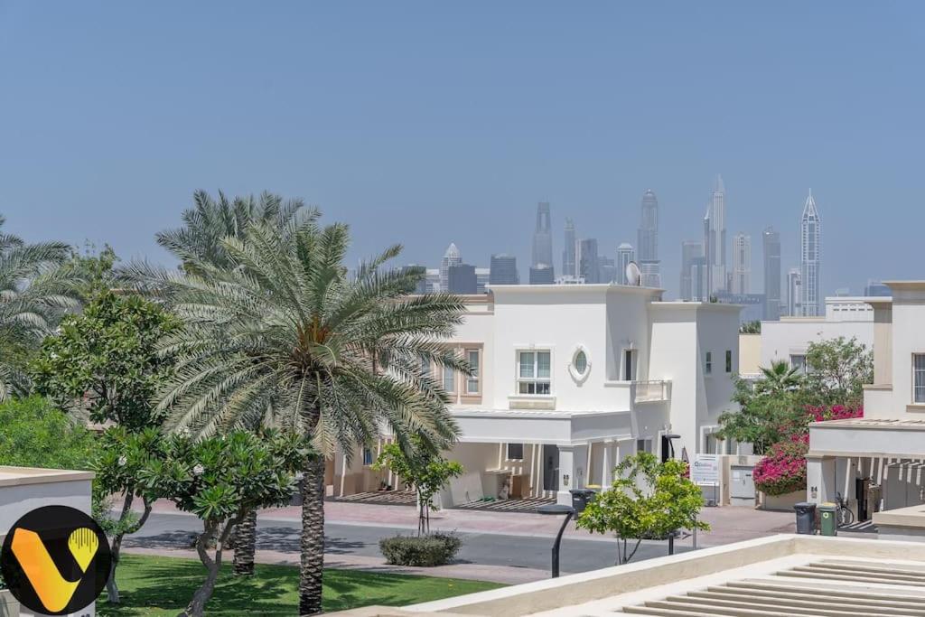 迪拜Vogue Villa Near Golf/Ski Dubai/ Ibn Battuta Mall的一座在城市前方有棕榈树的建筑