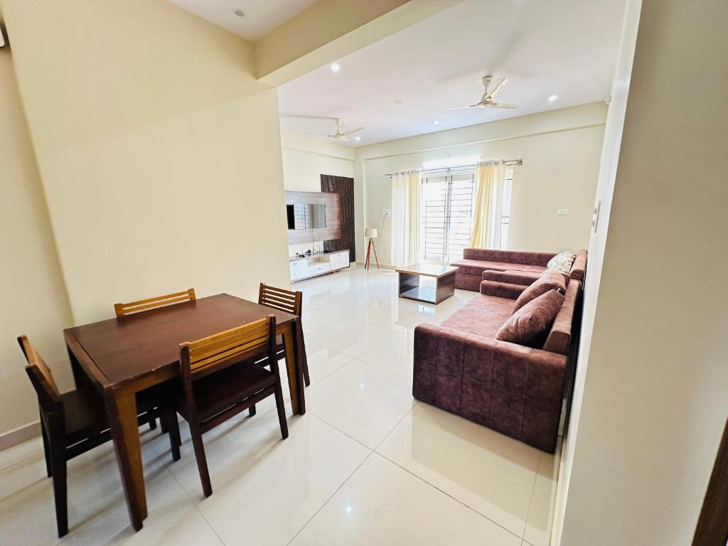 迈索尔Oryx Residences - Luxury Serviced Apartments的用餐室以及带桌子和沙发的客厅。