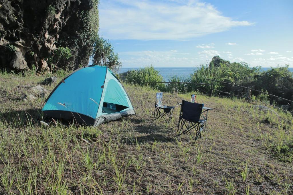 NgandongWisata Alam Lestari Gunung Semar的蓝色帐篷和田野上的两把椅子