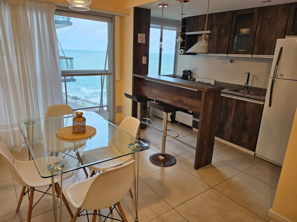 马德普拉塔Hermoso 2 ambientes en la costa con vista al mar的厨房配有玻璃桌、椅子和钢琴
