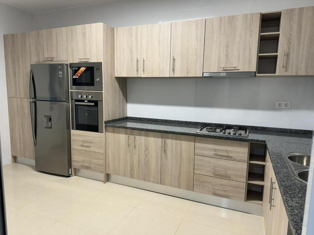 普拉亚BemVinda Sweet Home - Cama Mesa e Fogão的厨房配有木制橱柜和不锈钢冰箱。