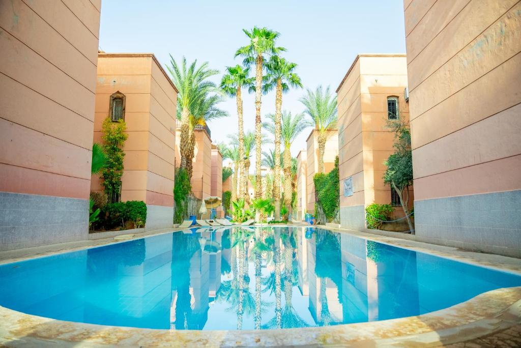 马拉喀什Riad The Moroccans Pool And Terrace的棕榈树建筑中的游泳池