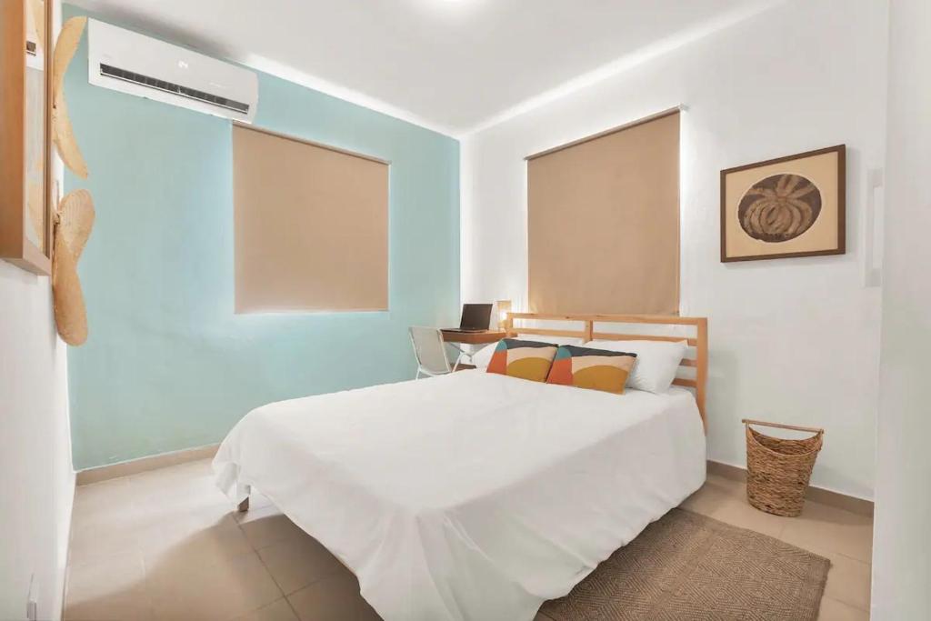 蓬塔卡纳OASIS Punta Cana Apartment的卧室配有白色的床和蓝色的墙壁