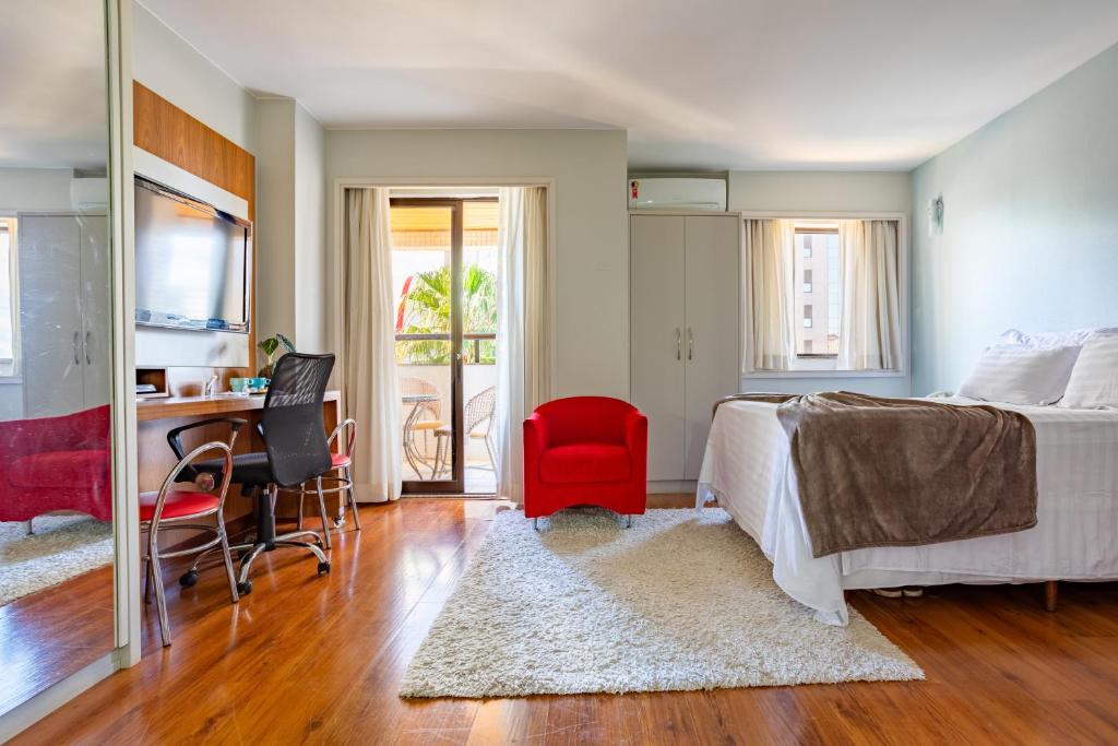 巴西利亚Flat - Comfort Suítes - Localização e Conforto的一间卧室配有一张床和一张带红色椅子的书桌