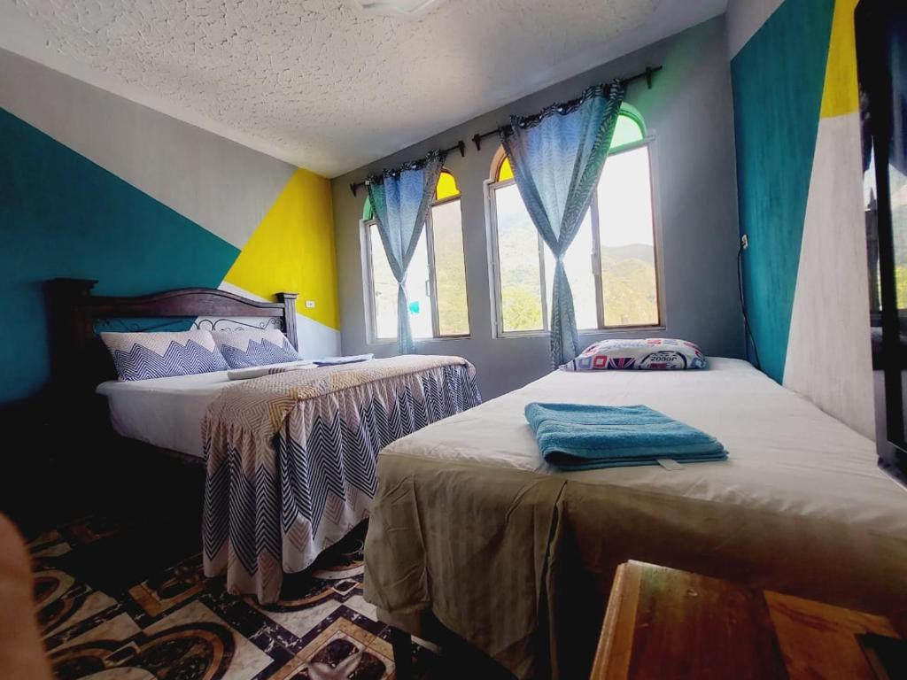 圣胡安拉拉古纳Alojamiento San Juan的配有色彩缤纷的墙壁和窗户的客房内的两张床