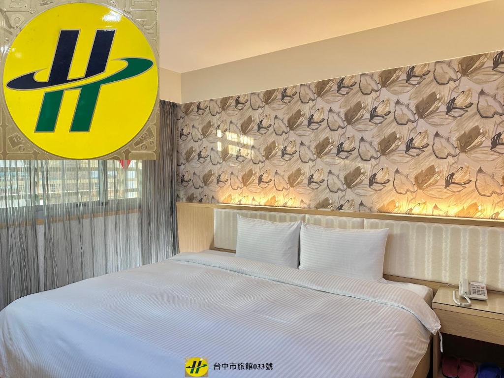 台中市美之旅商务饭店的酒店客房,设有一张床,墙上有标志