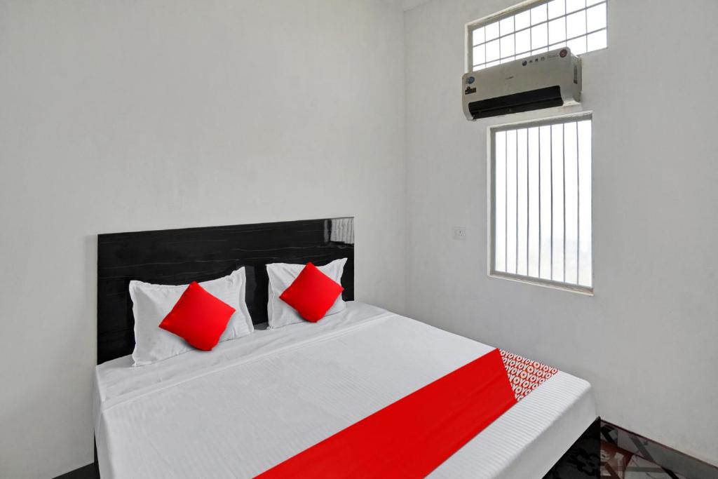 MurādnagarOYO Flagship Amazing Inn的一间卧室配有一张带红色枕头的床和一扇窗户