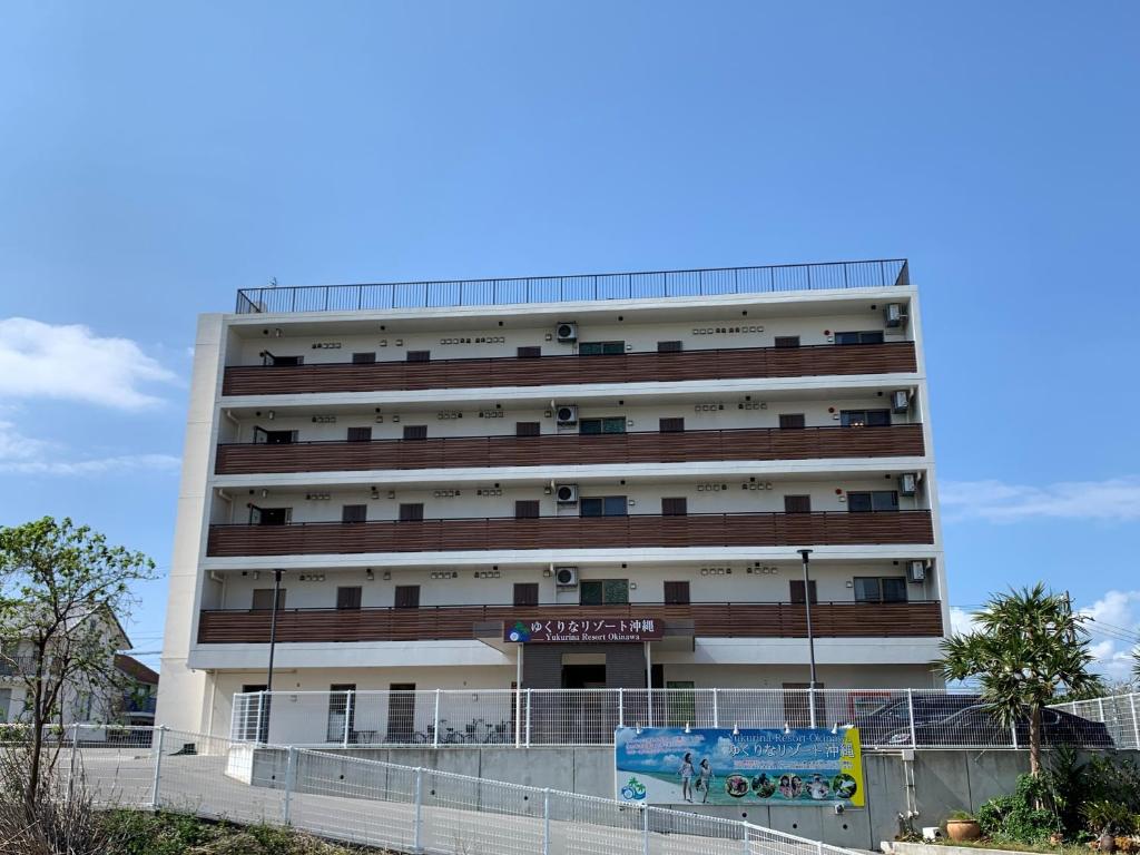 本部Yukurina Resort Okinawa的前面有栅栏的大白色建筑