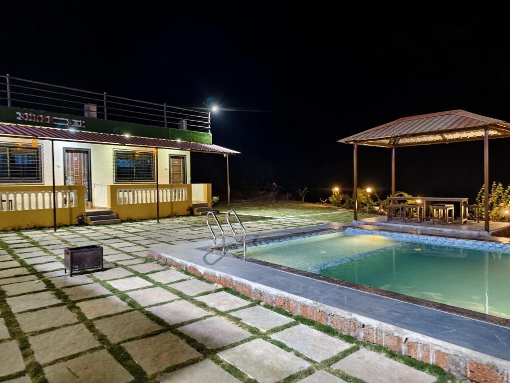 马哈巴莱斯赫瓦尔Shayadri Farmhouse的一座晚上设有游泳池的房子