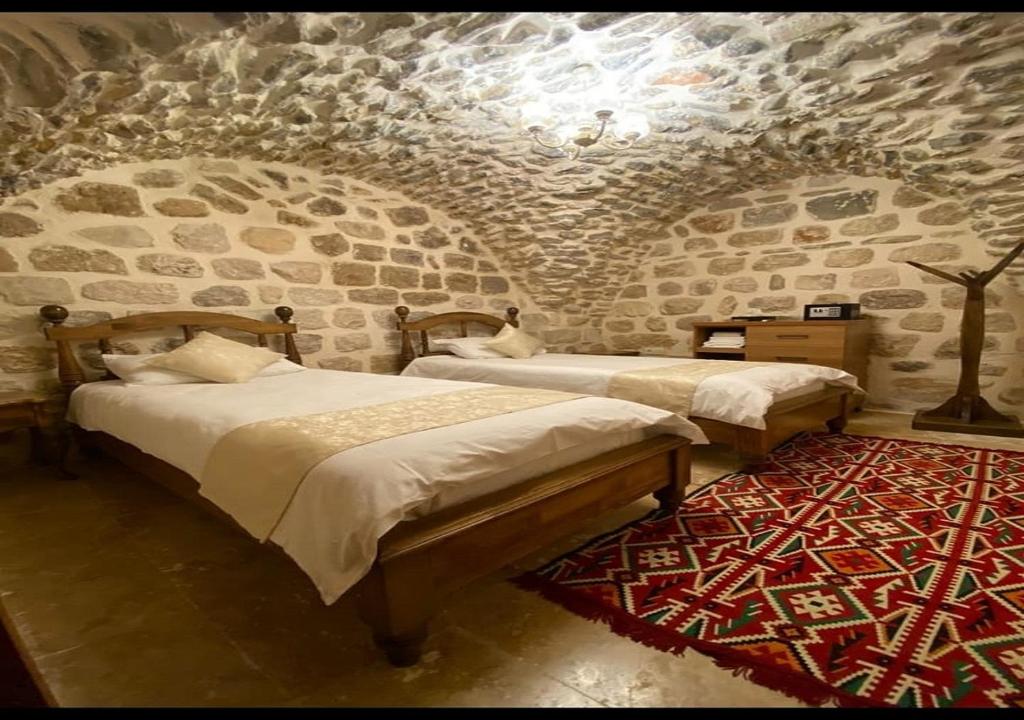 马尔丁Old City Tourism的一间设有两张床和石墙的房间