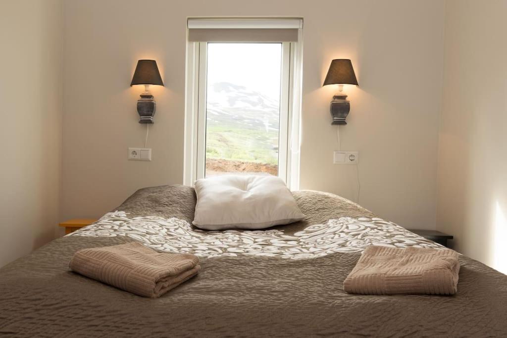阿克雷里Private cottage, elegance & amazing view的一间卧室配有带两个枕头的床和窗户
