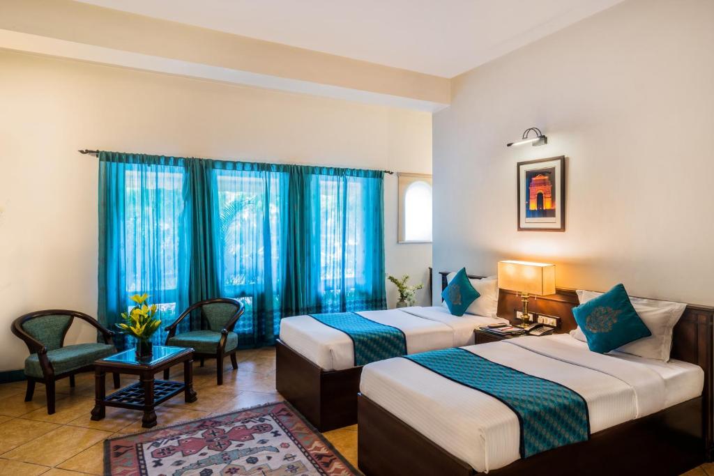 新德里Home@F37 Kailash Colony Metro的两张位于酒店客房的床,配有蓝色窗帘