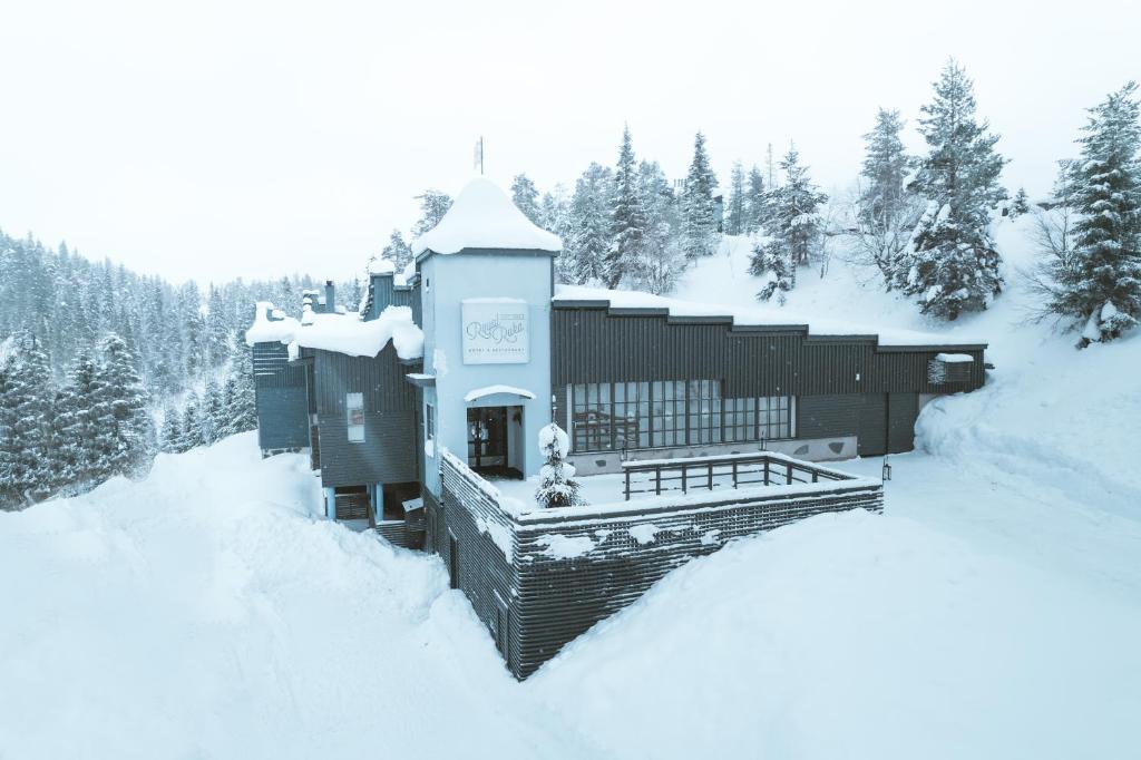 鲁卡皇家卢卡酒店的一座被雪覆盖的建筑,有树为背景