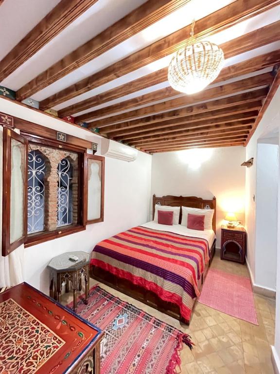 舍夫沙万达尔萨巴巴摩洛哥传统庭院住宅旅馆的一间卧室配有一张床和一个吊灯