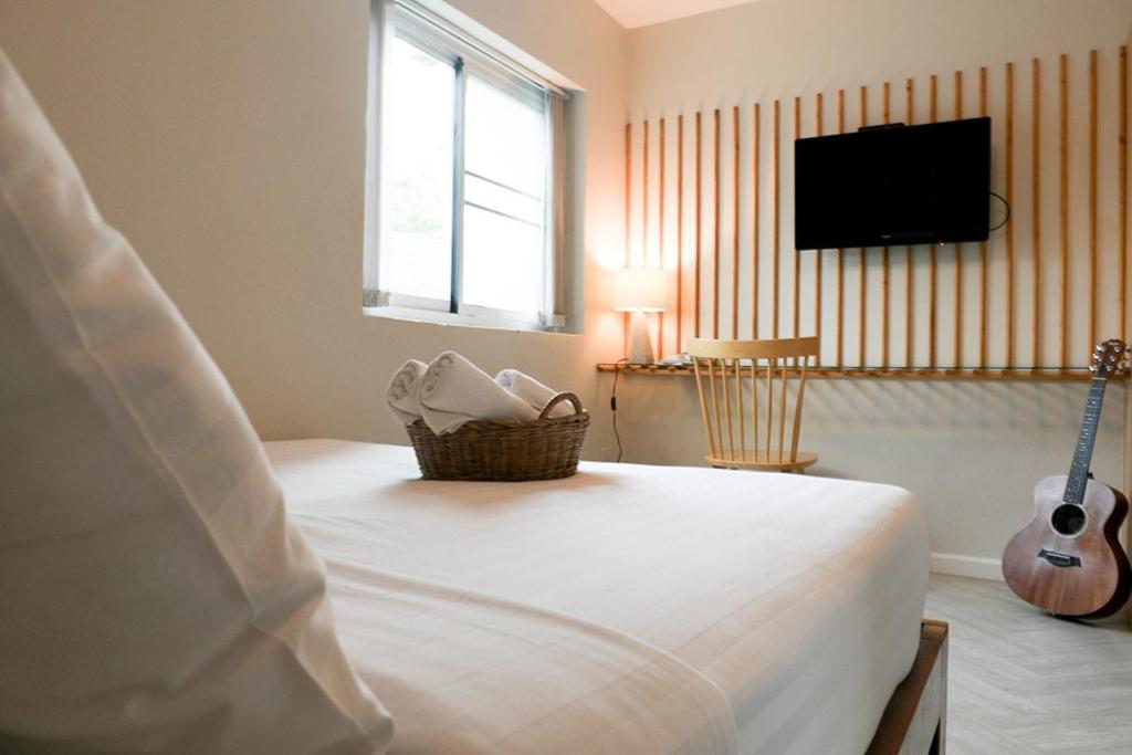 浦阿Shanti-Retreat Hotel的一间卧室配有一张床、一台电视和吉他