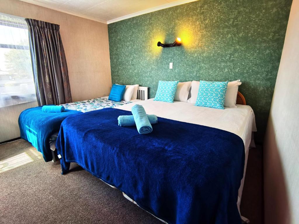 旺阿雷Denby Golf House Tikipunga的酒店客房,配有两张带蓝色床单的床