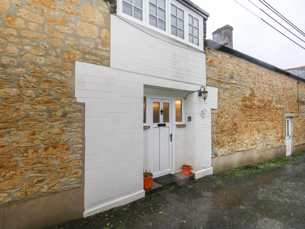 比明斯特Poppy Cottage的白色的房子,有门和石墙