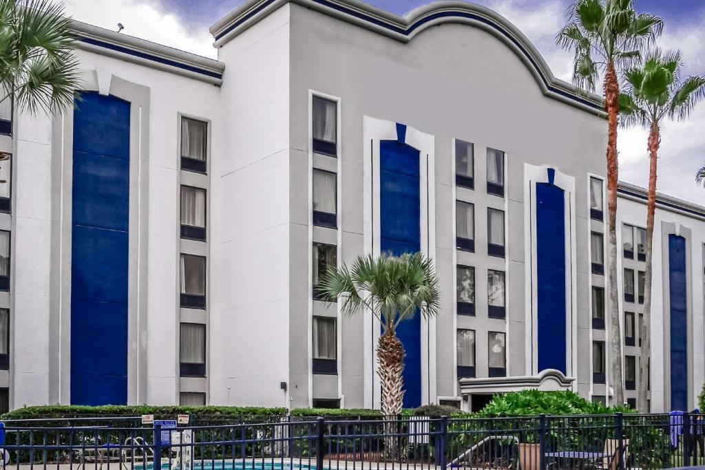 橘园Quality Inn Southside Jacksonville的一座拥有蓝色窗户和棕榈树的建筑