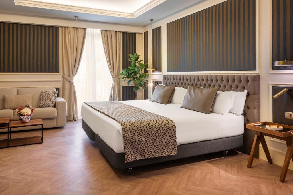 马德里加泰罗尼亚科尔特斯酒店的酒店客房,配有床和沙发