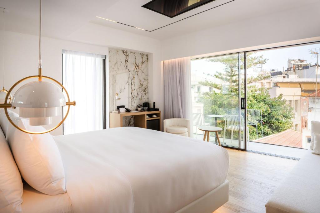 海若克利欧Ethereal White Resort Hotel & Spa的白色的卧室设有一张大床和一个大窗户