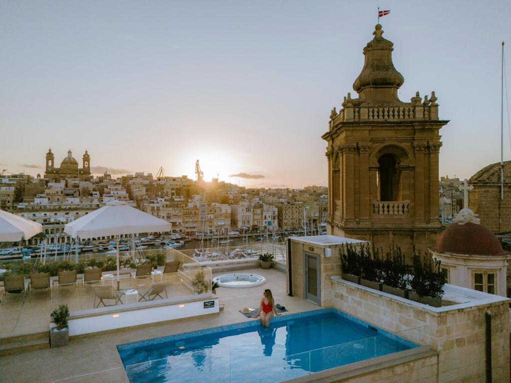 比尔古IBB Hotel Palazzo Bettina Malta的站在建筑物游泳池旁的女人