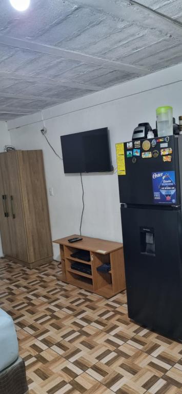 圣萨尔瓦多Apartatamento pequeño amueblado的客房设有冰箱、桌子和电视。