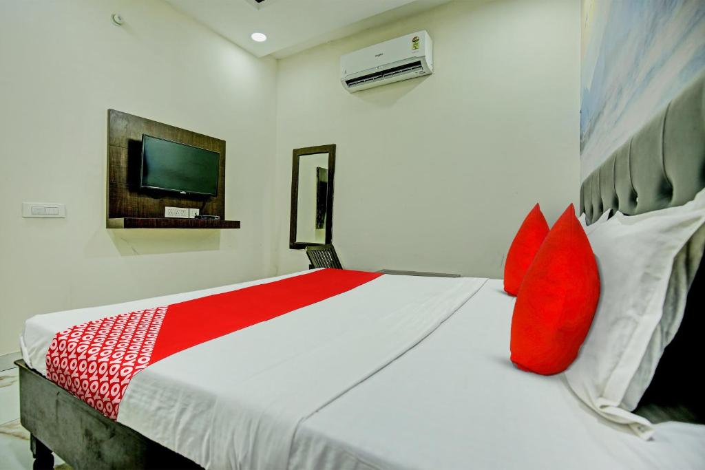 BamrauliOYO Flagship Hotel Sangam Palace的一间卧室配有一张带红色枕头的床和一台电视。