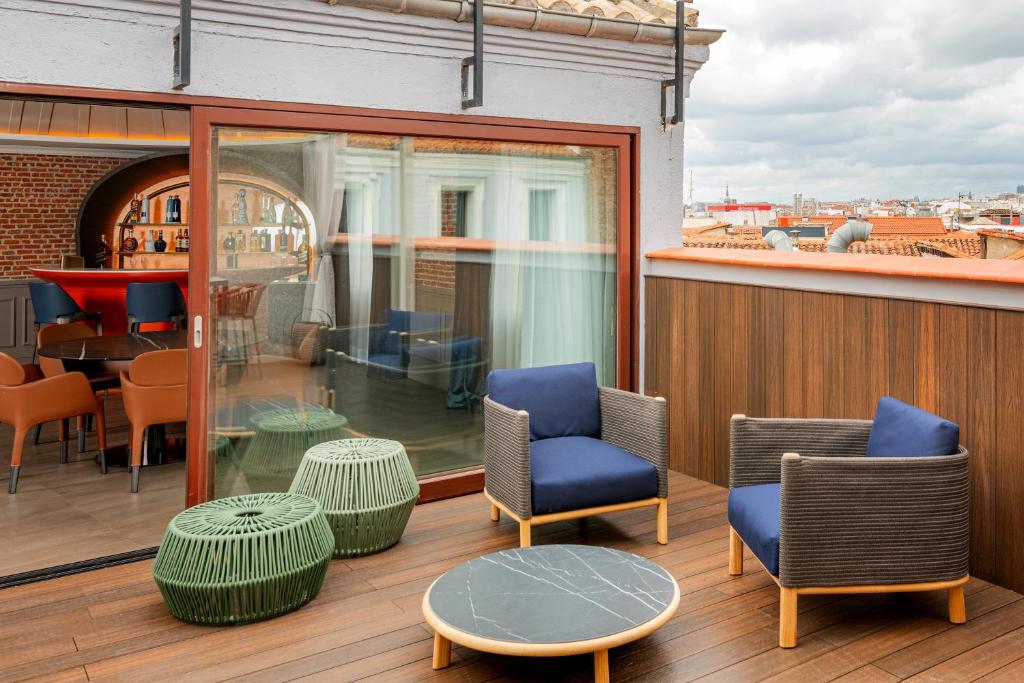 马德里Casa Faraona Luxury Residences的大楼内的阳台配有桌椅