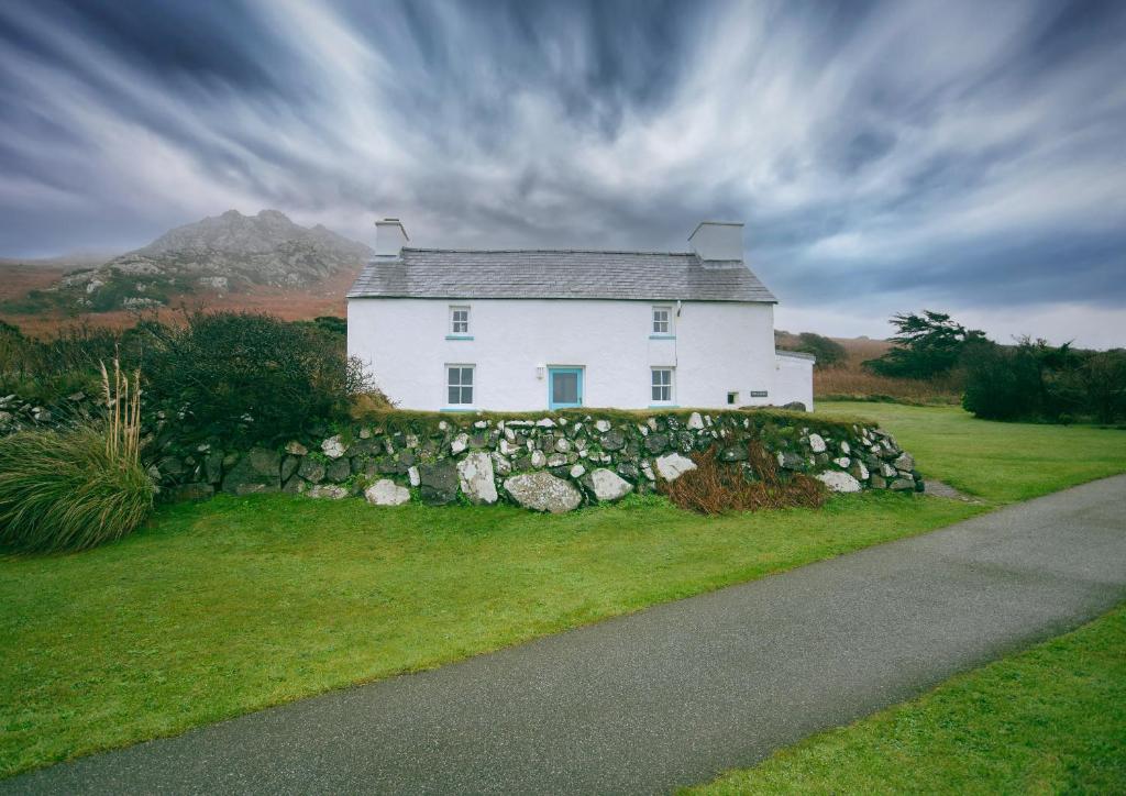 Saint NicholasTal y Gaer Cottage Goodwick的一座白色的山坡上的房子,有石墙