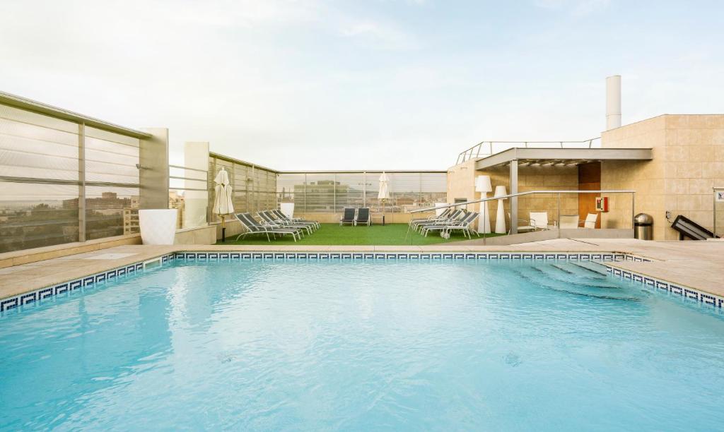 巴塞罗那伊鲁尼巴塞罗那酒店的一座大型蓝色游泳池,位于一座建筑的顶部