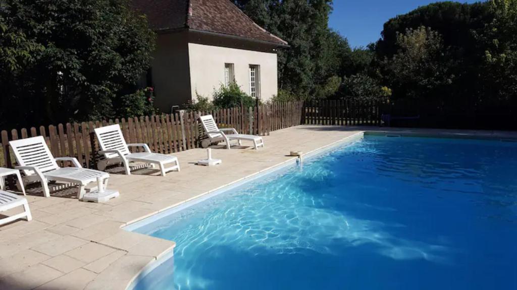 贝尔热拉克Le Chalet du Moulin Blanc的一个带椅子的游泳池以及一座房子