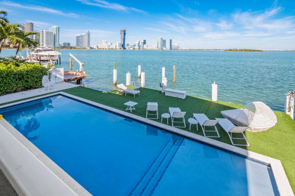 迈阿密Experience Opulence Your Exclusive Waterfront Sanctuary in Miami Beach的一个带椅子的游泳池,享有水景