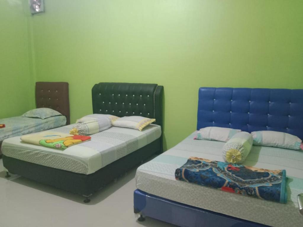Dukupenginapan alleo的绿墙客房内的两张床