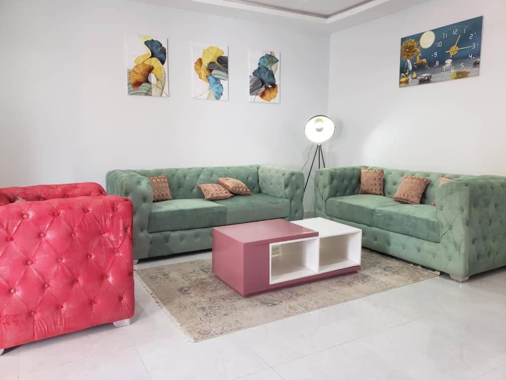 瓦加杜古Villa ECOGIB的客厅配有两张绿色沙发和一张粉红色的桌子