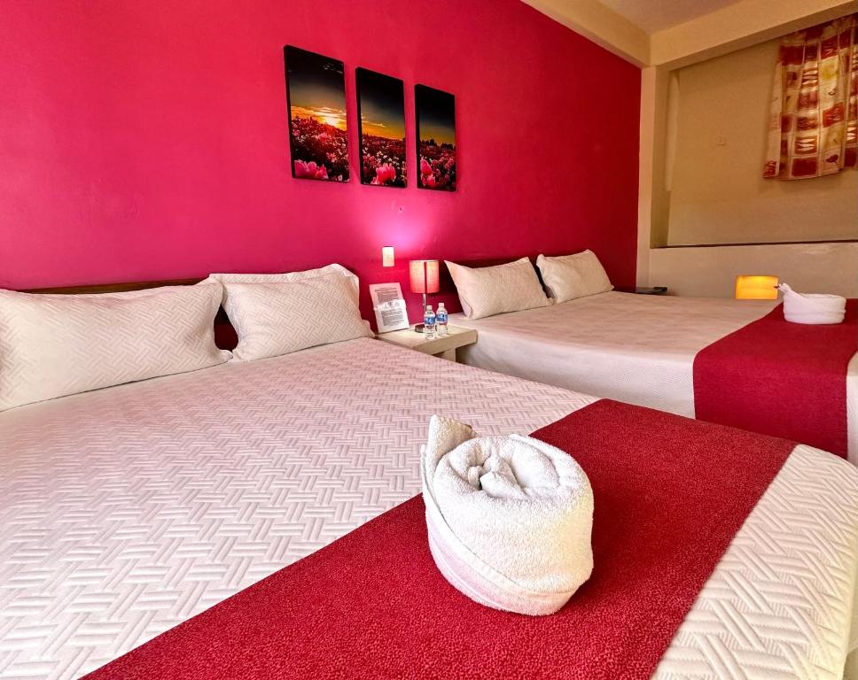 坎佩切巴兰基亚酒店的配有粉红色墙壁的客房内的两张床