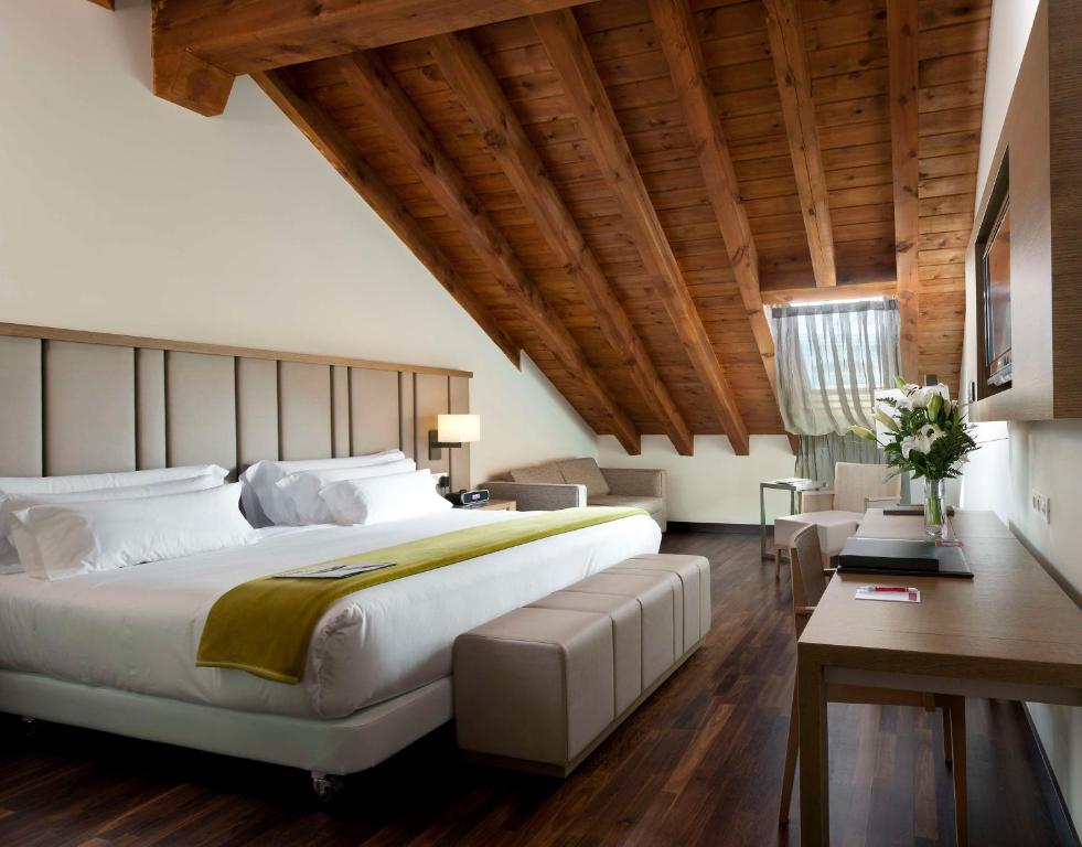 马德里帕拉西奥特帕NH精选酒店的一间卧室设有一张大床和木制天花板