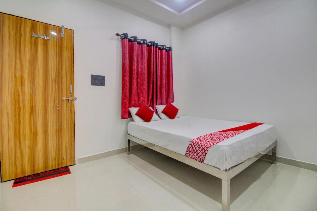 那格浦尔OYO Flagship Hotel Roman Inn的一间卧室配有一张带红色窗帘的床和一扇门