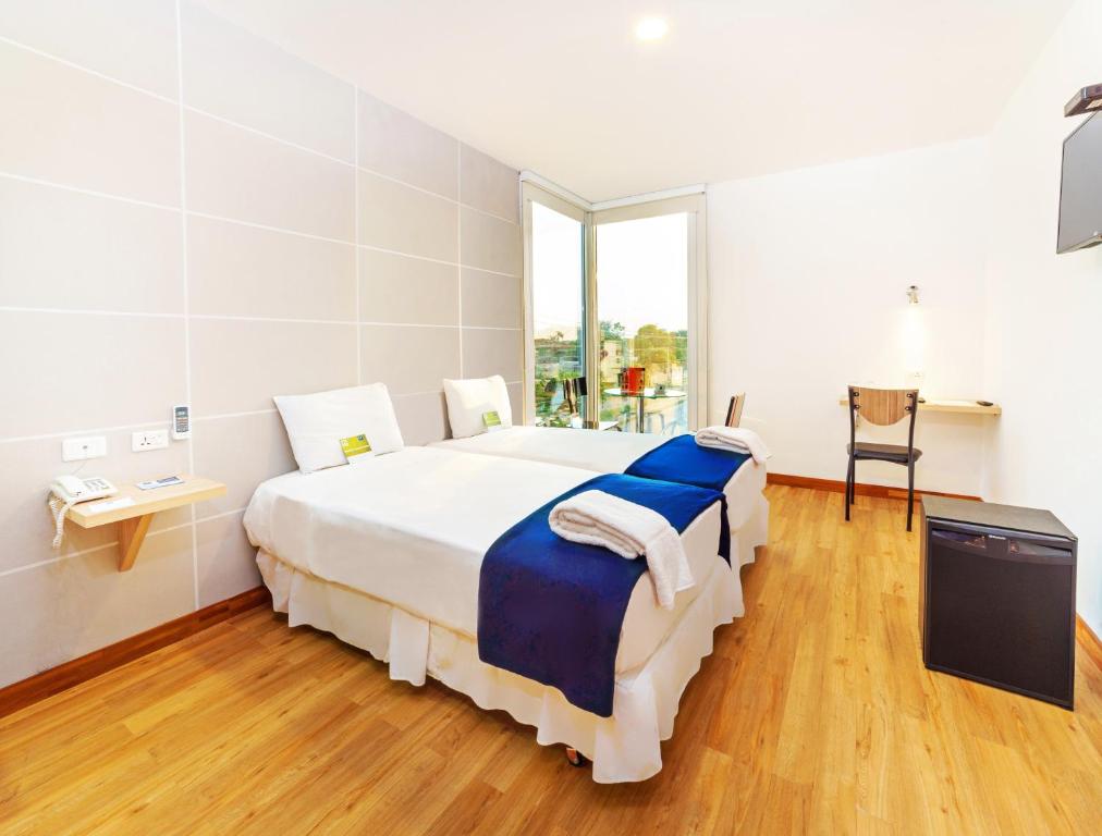 圣克鲁斯LP艾奎佩特罗酒店的一间白色的大卧室,配有一张带蓝色床单的大床