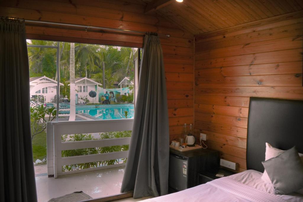 莫尔吉姆Seawood beach front resort的一间卧室设有一张床和一个享有游泳池景致的窗户。