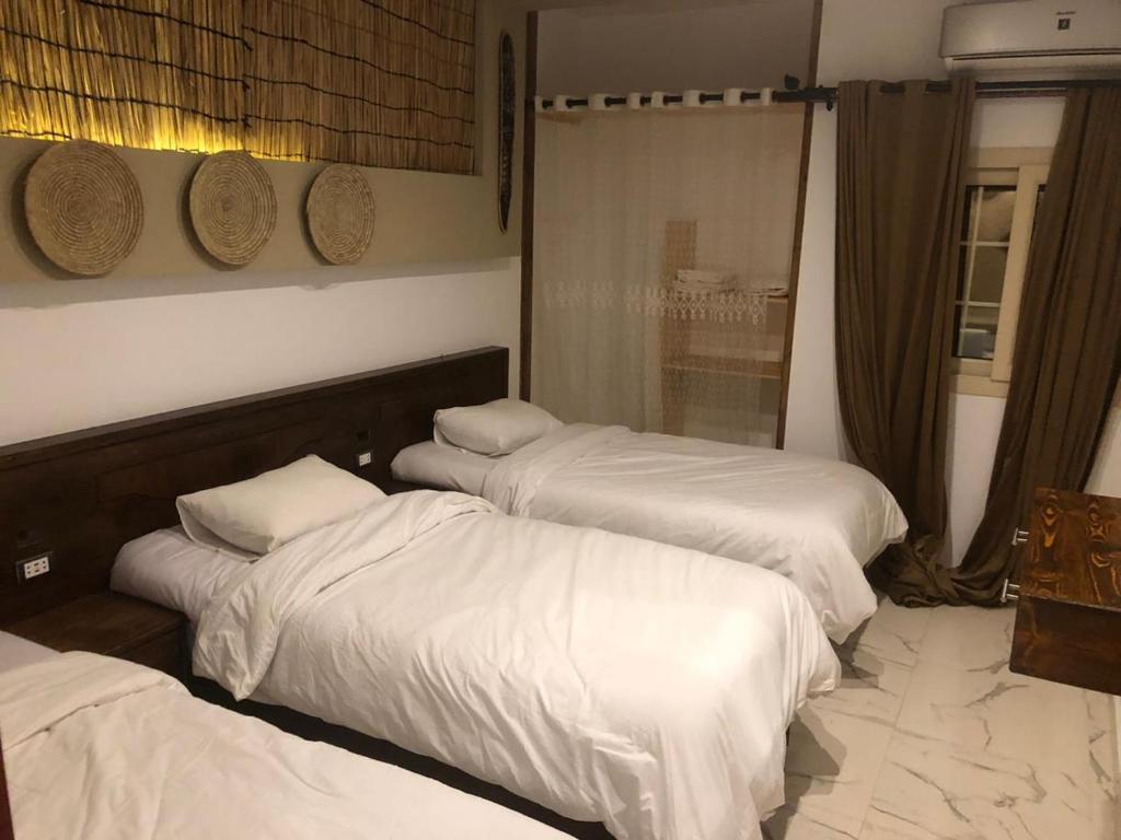 达哈布Laguna house的酒店客房内的三张床,配有白色床单