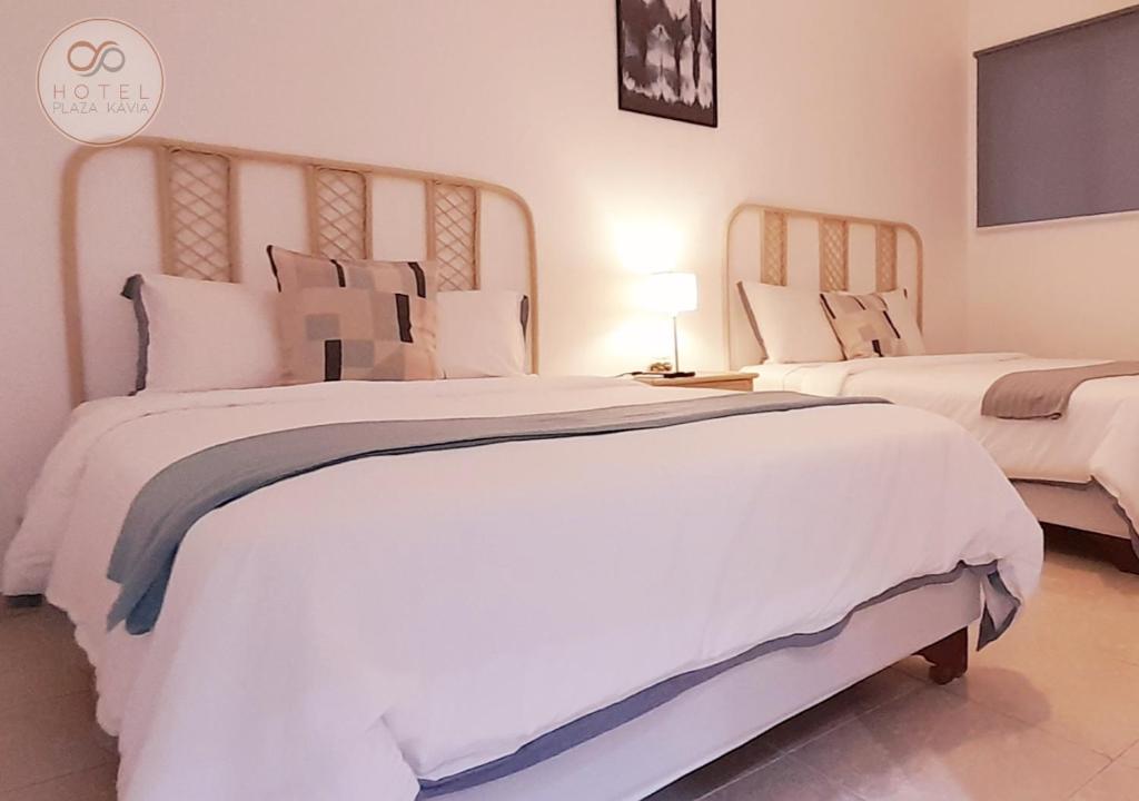 圣多明各Hotel Plaza Kavia的一间卧室配有两张大床,提供白色床单和枕头